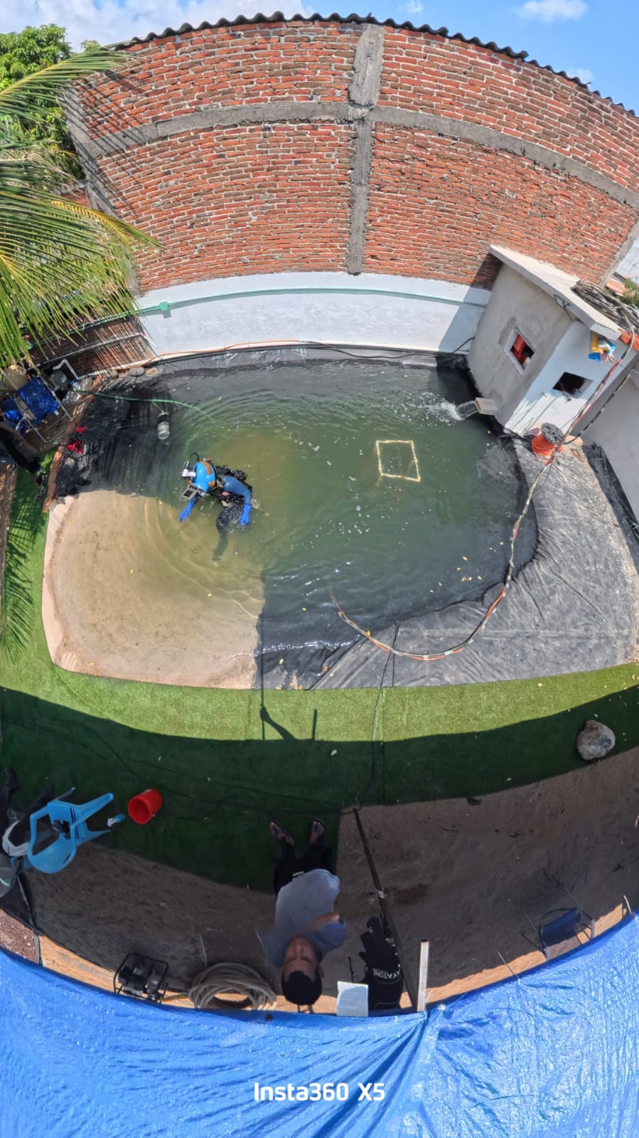 Buzo trabajando bajo el agua en la alberca, conectado por umbilical al equipo de superficie